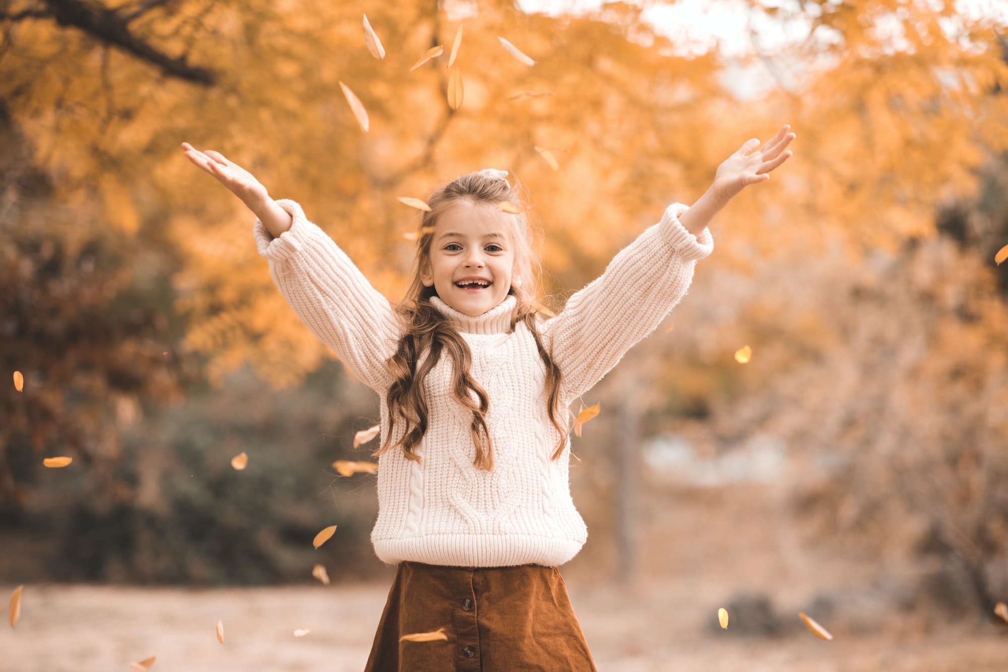 Happy child girl over yellow leaves in autumn park outdoor